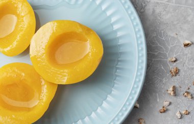 Mavi tabakta şerbetli dilimlenmiş sarı şeftali.