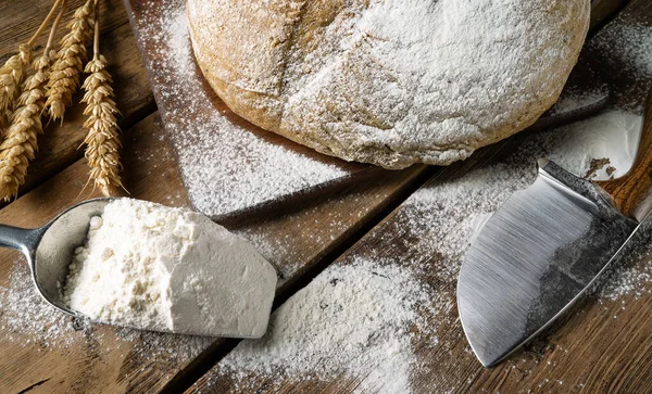 A round loaf of freshly baked sourdough bread flavored with hemp flour, with a knife on a cutting board. Craft bread with seeds on a dark table. Country style sourdough bread