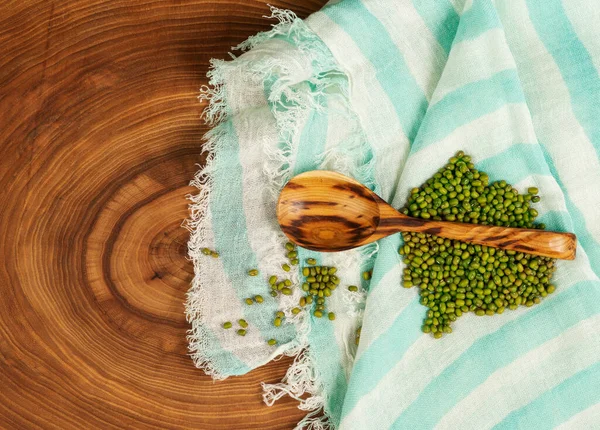 木のテクスチャの背景に隔離された木製のスプーンの中の豆 — ストック写真