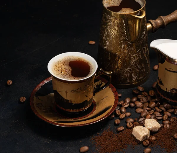 黒を背景にコーヒー豆とミルクマンの間でコーヒーとトルコのコーヒーポットのカップ ロイヤリティフリーのストック写真