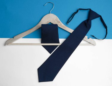 Beyaz ve mavi arka planda, ahşap bir askıda mavi kravat. Başarılı erkek stili konsepti