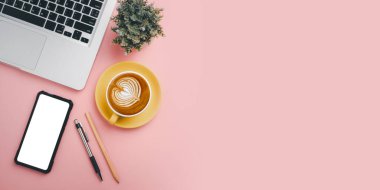 Bilgisayarlı ofis masası, boş ekran akıllı telefon, kalem, bitki, pembe arka planda kahve, fotokopi alanı olan üst görünüm,.