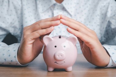 Domuz kumbarası, ahşap masanın üzerindeki koruma jesti, bağış toplama, kamu hizmetleri, üst yönetim, finansal kriz konsepti