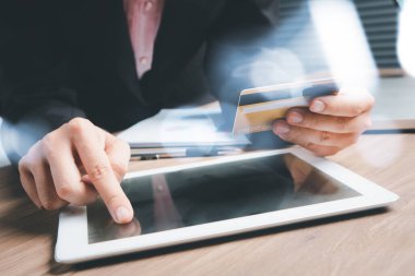 Kadının elinde kredi kartı var ve dijital tablet kullanıyor, online alışveriş yapıyor..
