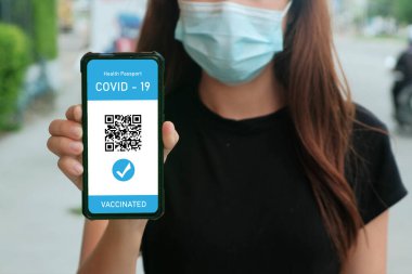 Kadın eli covid-19 salgını sırasında seyahat için cep telefonunda dijital sağlık pasaportu, covid-19 için aşı pasaportu, sağlık ve gözetim kavramları kullanıyor..