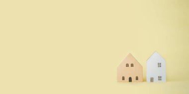 Miniature houses on yellow background with copyspace. Building blocks arranged in row.	