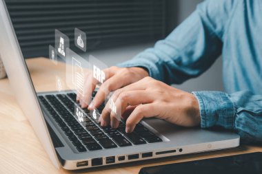 Atılgan Kaynak Planlama ERP, sanal ekrandaki simgelerle belge yönetimi kavramı, ofis masasındaki sanal ekranda dizüstü bilgisayarla çalışan iş kadını.