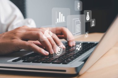 Atılgan Kaynak Planlama ERP, sanal ekrandaki simgelerle belge yönetimi kavramı, ofis masasındaki sanal ekranda dizüstü bilgisayarla çalışan iş kadını.