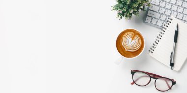 Office desk with keyboard computer, pen, eyeglass, notebook, Cup of coffee on white background, Top view with copy space, Mock up.	