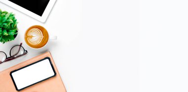 Boş ekranlı akıllı telefon, tablet, not defteri beyaz arka planda kahve fincanı, fotokopi alanı olan üst görünümü olan ofis masası.