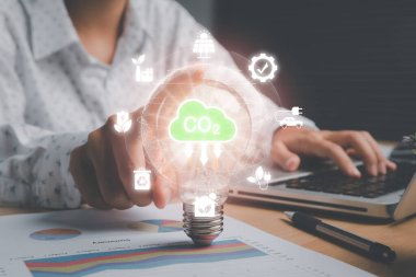 CO2 emisyon kavramını azaltmak, sanal ekranda CO2 simgesiyle el ele tutuşan kişi, yenilenebilir enerji ve elektrik taşımacılığına dayalı sürdürülebilir kalkınma ve yeşil iş.