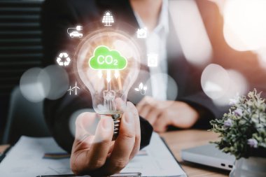CO2 emisyon kavramını azaltmak, sanal ekranda CO2 simgesiyle el ele tutuşan kişi, yenilenebilir enerji ve elektrik taşımacılığına dayalı sürdürülebilir kalkınma ve yeşil iş.