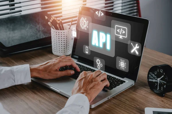 API - Application Programming Interface, Man using laptop computer with touch screen interface and select API icon, Software development tool, modern technology, internet and networking concept.