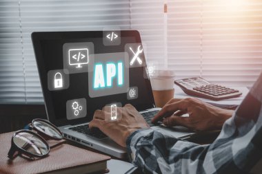 API - Uygulama Programlama Arayüzü, Dokunmatik ekranlı dizüstü bilgisayar kullanan ve API simgesi, Yazılım geliştirme aracı, modern teknoloji, internet ve ağ oluşturma.