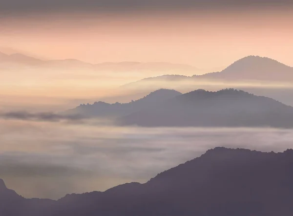 Sisli dağların ardında, gölgede yüzen sisli dağların ardında güzel bir günbatımı.