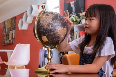 Kız eğlence olsun diye sahte bir küre çeviriyor. Çocuklar fen dersinde okuyor. Kızlar kafede oyuncaklarla oynuyorlar..