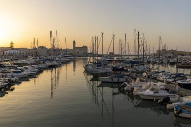 Trani şehir limanı yazın gün batımında ve Trani katedrali arka planda, Puglia, İtalya.