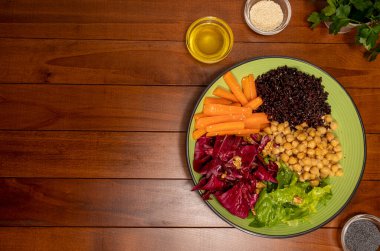 Buda kasesi ahşap masada. Vejetaryen yemeği. Akdeniz diyeti. Sağlıklı beslen. Yaz yemekleri. Renkli yemekler. Bir tabak nohut, siyah pirinç, havuç, kırmızı salata ve marul. Düz yatıyordu. Boşluğu kopyala.