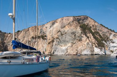 Uçurumun kenarında bir yelkenli. Yazın Ponza adasının kayalık uçurumunda.
