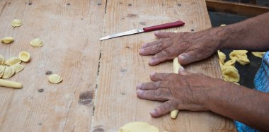 Knead the homemade orecchiette baresi. Typical fresh pasta from Bari, Puglia region, Italy. Working hands. Hands of an old woman. Italian small business owners. Ancient tradition.
