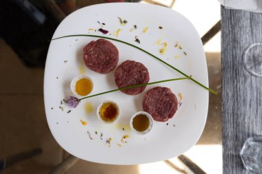 Beyaz bir tabakta sığır etli tartar ve yanında soslar. Çiğ et.