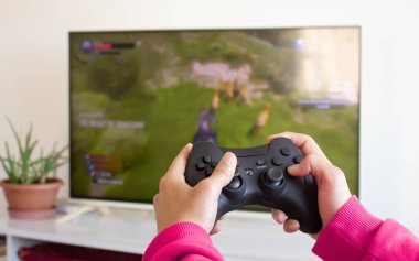 Kız video oyunu oynuyor, kız elleri konsol oyun sahasını televizyona karşı tutuyor ve evde konsol oyunu oynuyor. Oyun, hafta sonu eğlence konsepti