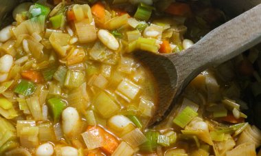 Ahşap kaşıklı yakın plan sebze çorbası, üst manzara. Soğanlı çorba, havuç, domates, fasulye, pırasa. Evde vejetaryen yemekleri.