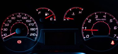 Car dashboard. Instrument panel with speedometer, tachometer, fuel gauge, oil temperature, seat belt with red arrow on black. Modern car interior details.