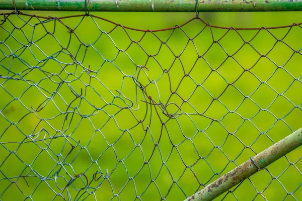 broken mesh wire fence in the field