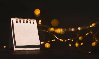 Kapat, boş sayfa takvimi altın bokeh ile siyah zemin üzerinde.