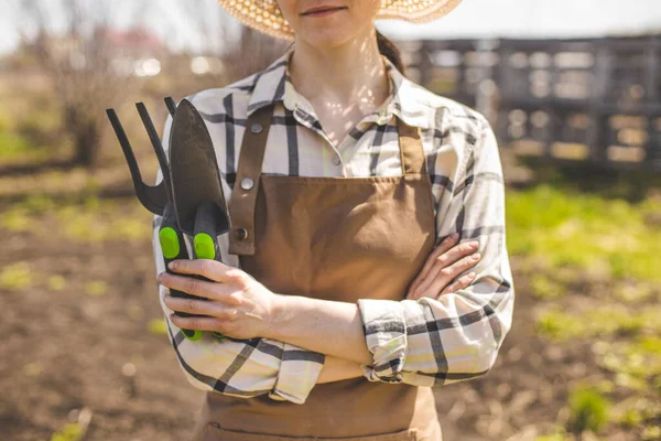 Boer met gereedschap in haar handen, werkzaam in biologische groentetuin — Stockfoto