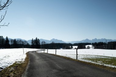 Karlı tarlalardan dağlara giden asfalt yol.