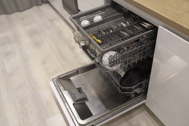 Open dishwasher with clean dishes at home white kitchen 
