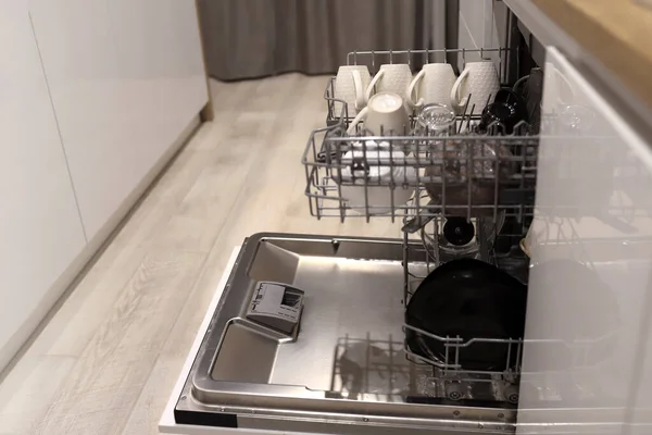 Відкрита посудомийна машина з чистим посудом після миття на сучасній скандинавській кухні . — стокове фото