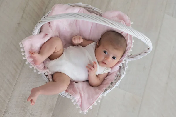 Bebê sorridente está deitado em uma cesta branca — Fotografia de Stock