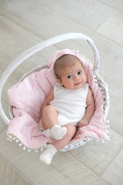 Bebê sorridente está deitado em uma cesta branca. conceito de uma criança saudável — Fotografia de Stock