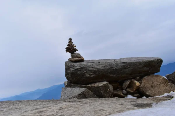 Balance rock structure on top of a mountain with panoramic view of valley in Chopta, Uttarakhand. Stone balancing.