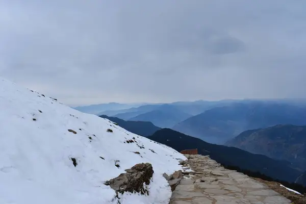 Mountain trail path with snow in winter at Tungnath trek Uttarakhand India. beautiful mountain landscape in the mountains.