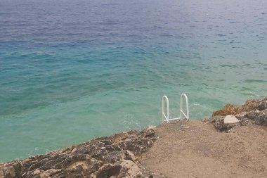 Deniz ve sahil, dalgalar ve arkada mavi su.