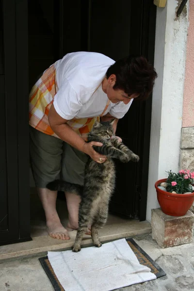 a woman with a cat that she raised on its hind legs, Baska, island Krk, Croatia