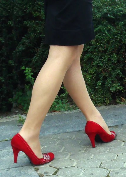 穿着红色高跟鞋 黑色短裙 脚踩着沥青的年轻女士的腿 — 图库照片