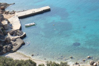 Kıyıya demirlemiş bir teknesi ve taş yaklaşımı ve iskelesi olan bir deniz körfezi, ada Rab, Hırvatistan