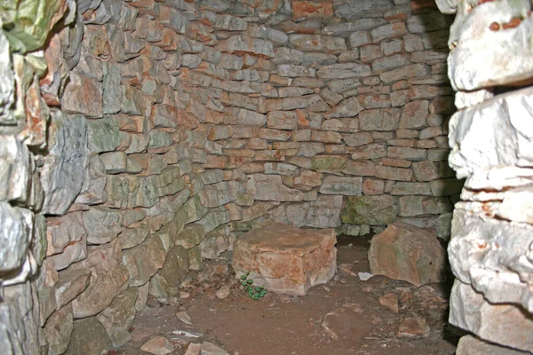 Interior of an old stone house called BUNJA or KAZUN in a field with a stone chair, Croatian coast and islands