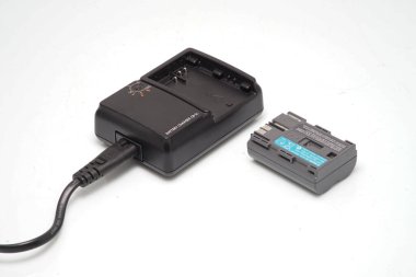 Kameranın bataryası ve bataryası için şarj cihazı beyaz arka planda izole edilmiş.