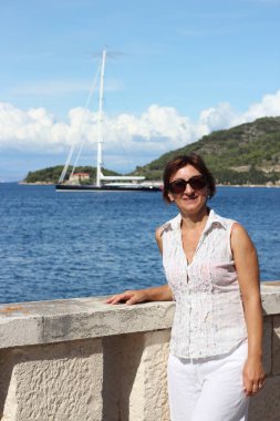 Deniz kenarında güneşli bir günde bir kadın poz veriyor.