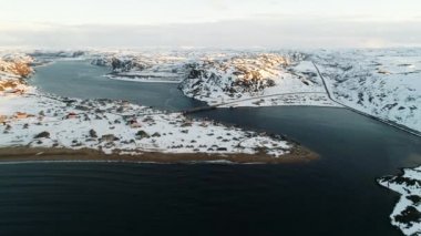 İnsansız hava aracı Kuzey Denizi körfezindeki balıkçı köyünün üzerinden uçuyor. Köprü adayı anakaraya bağlıyor. Kola Yarımadası 'nın sert iklimi. Teriberka 'nın karla kaplı kıyıları