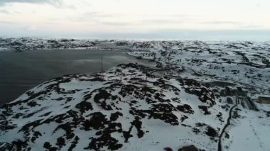 İnsansız hava aracı karla kaplı uçurumlarla çevrili, kuzeydeki küçük bir kasabadaki iletişim kulelerine doğru uçuyor. Barents Denizi kıyısındaki Teriberka köyü. Sert kuzey iklimi.