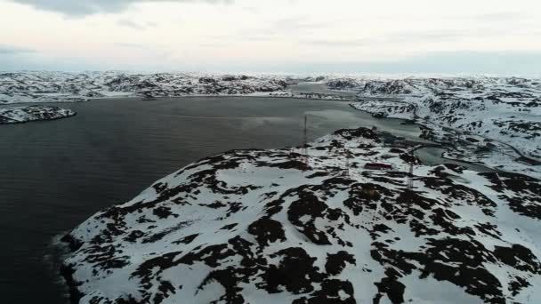 Drone voando sobre as margens da península de Kola no inverno. Rochas cobertas de neve, águas frias do Oceano Ártico. A aldeia de Teriberka na margem do Mar de Barents — Vídeo de Stock
