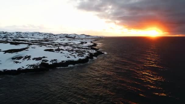 Un beau coucher de soleil sur l'océan, le soleil est couvert de nuages orageux. Le drone vole dans les eaux noires de l'océan qui baignent la côte rocheuse de la Scandinavie ou de l'Amérique du Nord. Océan Arctique — Video