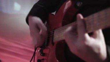 Bir müzisyenin ışık müziğinde çaldığı elektro gitarın yakın çekimi. Kundakçı bir rock grubunun müzisyeni gitar çalıyor. Bir gece kulübündeki konserde müzik grubunun performansları.